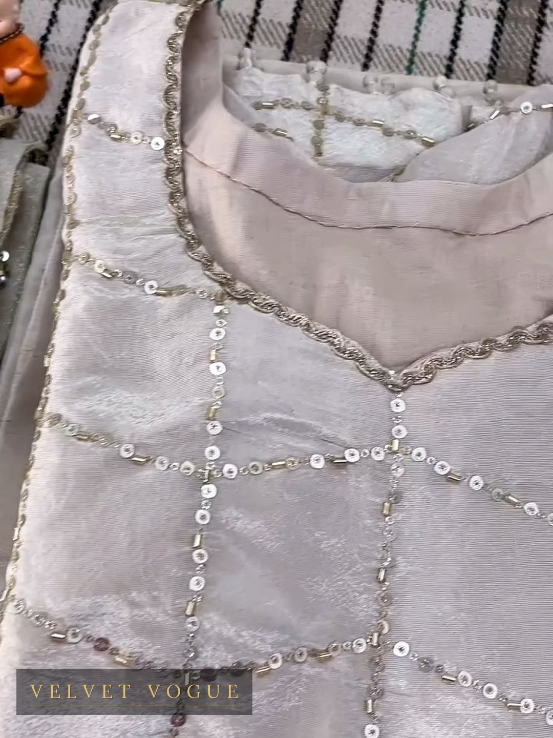 A sequin lattice set square across champagne tissue, with a gold cord scallop shaping the neck.