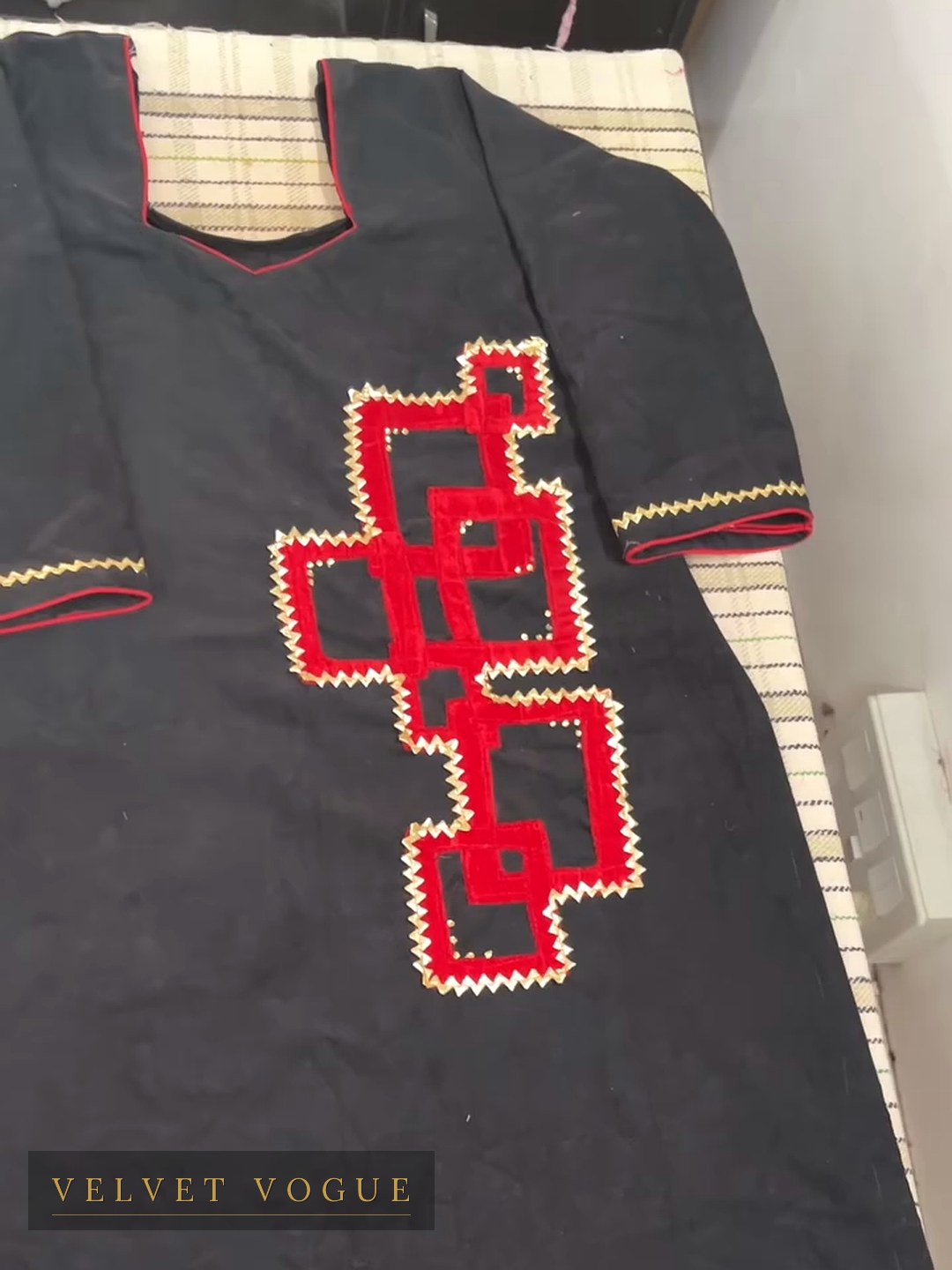 Red appliqué laid onto black and outlined in a hand-run zigzag — a Phulkari figure, reworked.