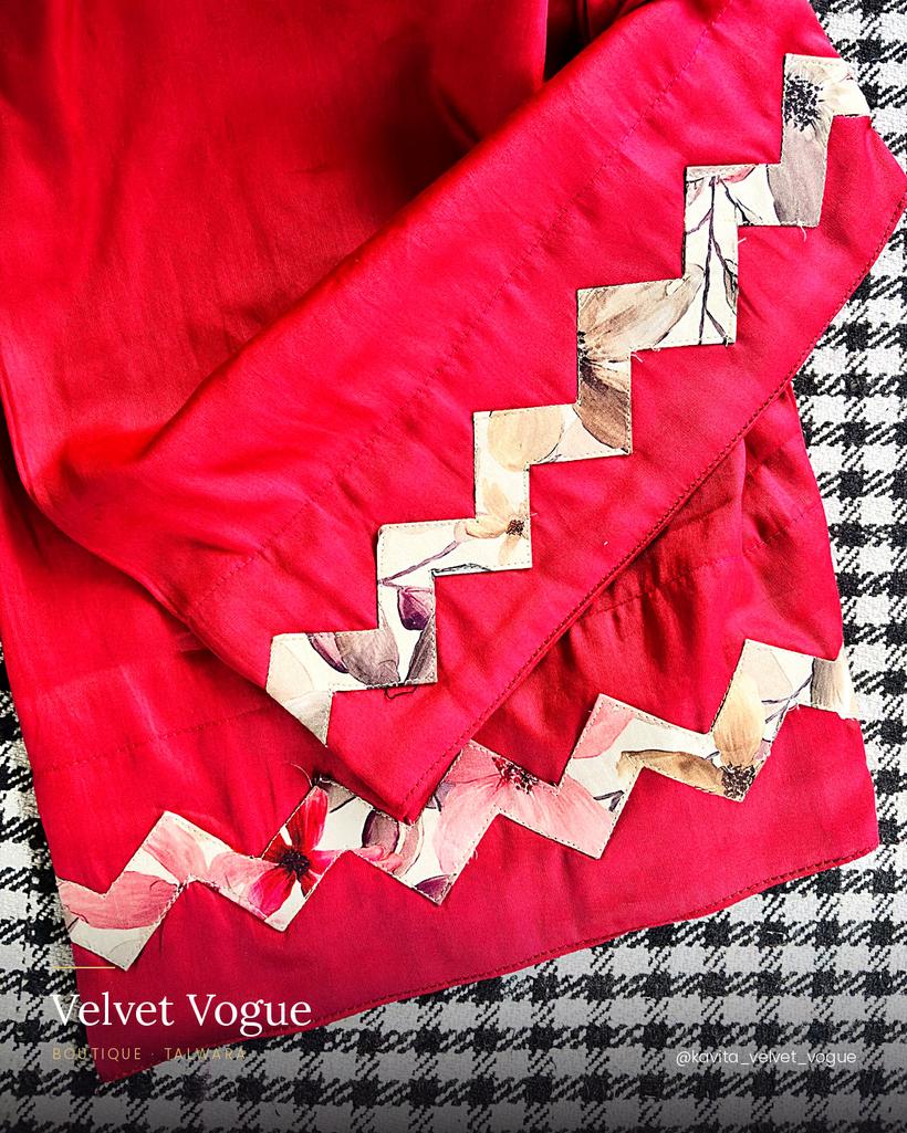 Red and floral appliqué run as a zigzag border — every piece cut by hand.